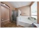 Well-lit bathroom with a soaking tub, shower stall, and neutral color palette at 10414 W Windsor Ave, Avondale, AZ 85392