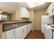 Kitchen features stainless steel sink, white cabinetry and appliances with wood-look flooring at 11375 E Sahuaro Dr # 1055, Scottsdale, AZ 85259