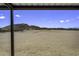 Covered patio view of the expansive, sandy and fenced yard and mountain backdrop at 13050 N Breeze Way, Maricopa, AZ 85139