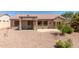 Home backyard with covered patio, desert rock landscaping, and views of lush vegetation at 15874 W Wildflower Dr, Surprise, AZ 85374