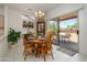 Bright dining area with a round wooden table, complemented by tile flooring and sliding glass doors to the patio at 16354 W Labyrinth Ln, Surprise, AZ 85374