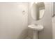 Neat half bathroom featuring a pedestal sink and a round mirror at 17493 N Costa Brava Ave, Maricopa, AZ 85139