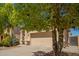 Home with a large tree in front with a two-car garage, desert landscaping at 17493 N Costa Brava Ave, Maricopa, AZ 85139