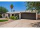 Home exterior showcasing well-maintained landscaping, a dark-colored garage door, and a circular garden at 3839 E Friess Dr, Phoenix, AZ 85032