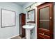 Powder room with pedestal sink, dark wood cabinetry, and vintage lighting at 4135 E Altadena Ave, Phoenix, AZ 85028