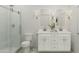Modern bathroom featuring double sinks, white cabinetry, and a sleek glass shower enclosure at 42515 W Peters Dr, Maricopa, AZ 85138