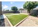 Green backyard with artificial turf, a concrete patio, mature trees, and gravel border at 626 W Tallula Trl, San Tan Valley, AZ 85140