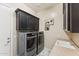 Efficient laundry room with modern washer and dryer, upper cabinets, and a utility sink at 7511 S Parkcrest St, Gilbert, AZ 85298