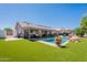 A spacious backyard featuring a swimming pool, covered patio, artificial turf, and mature landscaping at 823 N 81St St, Mesa, AZ 85207