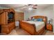Bedroom features a large wooden bed frame, ceiling fan, and custom cabinet for TV and storage at 823 N 81St St, Mesa, AZ 85207
