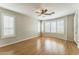 A serene bedroom featuring hardwood floors, a ceiling fan, and large windows with shutter blinds at 8503 W Coyote Dr, Peoria, AZ 85383