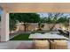 Covered outdoor dining area overlooks the lush backyard with artificial turf and mature trees at 16238 N 58Th St, Scottsdale, AZ 85254