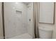 Bright bathroom featuring a white-tiled shower with built-in niche and penny tile flooring at 16421 N 34Th Ave, Phoenix, AZ 85053