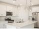 Bright kitchen featuring an island with quartz countertops and stainless steel appliances at 19406 N Fiano Dr, Maricopa, AZ 85138