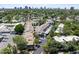 An aerial view of neighborhood townhomes featuring lush landscaping, mature trees, and a city skyline in the background at 2946 N 14Th St # 3, Phoenix, AZ 85014