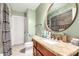 Bathroom features a wooden vanity with stone top, stylish oval mirror, and a shower with patterned curtain at 3842 W Ocotillo Rd, Phoenix, AZ 85019