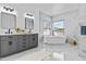 Modern bathroom features marble walls, a gray double vanity, and a freestanding soaking tub at 38709 N 16Th Pl, Phoenix, AZ 85086