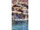 Close-up of a rock waterfall flowing into a backyard pool offering serene sounds and refreshing waters at 4093 E Westchester Dr, Chandler, AZ 85249