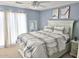 Cozy bedroom with light blue walls, a comfy bed with patterned linens, and natural light streaming through sheer curtains at 44583 W Sandstone Dr, Maricopa, AZ 85139