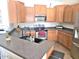 Well-lit kitchen with wood cabinets, stainless steel appliances, and dark countertops with a double basin sink at 44583 W Sandstone Dr, Maricopa, AZ 85139