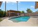 Sparkling pool with a pergola, surrounded by lush landscaping and clear blue skies at 5227 W Acapulco Ln, Glendale, AZ 85306