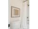 Close-up of a toilet, art and shower featuring a white shower curtain and brushed metal fixtures at 8541 W Sierra Vista Dr, Glendale, AZ 85305