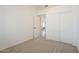 A bright bedroom with neutral carpet and closet featuring an open door to another room at 8541 W Sierra Vista Dr, Glendale, AZ 85305