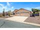 Attractive single-story residence featuring desert landscaping and a spacious driveway leading to a three-car garage at 10214 E Moonshadow Way, Gold Canyon, AZ 85118