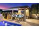 Backyard outdoor kitchen with BBQ, countertop seating, built-in bar, and roll down shade at 11796 W Creosote Dr, Peoria, AZ 85383