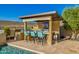 Outdoor kitchen with bar seating, BBQ, and tv, next to a swimming pool and desert landscape at 11796 W Creosote Dr, Peoria, AZ 85383