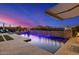 Resort-style backyard oasis featuring a pool with water features and mountain views at twilight at 11796 W Creosote Dr, Peoria, AZ 85383