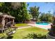 Lush backyard with a pool, cabana, and a hanging chair create a relaxing and inviting outdoor space at 1204 S Arroya Cir, Mesa, AZ 85206