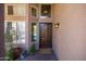 Inviting front entryway with wood door, sidelight windows, potted plants and warm exterior lighting at 1204 S Arroya Cir, Mesa, AZ 85206