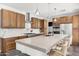 Open-concept kitchen boasts wood cabinetry, stainless steel appliances, a large island with seating, and modern pendant lighting at 1204 S Arroya Cir, Mesa, AZ 85206