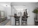 Kitchen bar with seating, open to a dining area and neutral grey walls at 15971 W Indigo Ln, Surprise, AZ 85374