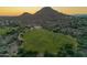 Scenic aerial view of a community with lush green spaces and mountain views at sunset at 1935 E Seminole Dr, Phoenix, AZ 85022