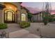 Inviting front entrance with a decorative iron door, lush landscaping, and stone accents at 1935 E Seminole Dr, Phoenix, AZ 85022