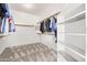 A large walk-in closet with carpet flooring, white shelving, and hanging clothes at 1935 E Seminole Dr, Phoenix, AZ 85022