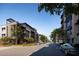 Contemporary condo buildings line a quiet street with parked cars and well-maintained landscaping and blue skies at 19360 N 73Rd St # 1069, Scottsdale, AZ 85255