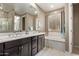 Bathroom featuring double sinks, large mirror, soaking tub, and neutral color palette at 226 E Monza Way, San Tan Valley, AZ 85140
