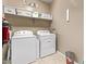 Functional laundry room with white washer, dryer, storage shelf, and tile floor at 226 E Monza Way, San Tan Valley, AZ 85140