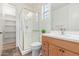 Bright bathroom featuring a glass enclosed shower, single sink vanity, and window at 29007 N 120Th Dr, Peoria, AZ 85383