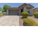 Charming single-story home featuring a stone facade, lush landscaping, and a paved driveway leading to the garage at 29007 N 120Th Dr, Peoria, AZ 85383