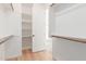 Bright walk-in closet featuring wood floors, shelves and rods, with a doorway to the bathroom at 29007 N 120Th Dr, Peoria, AZ 85383