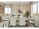 This dining room boasts a wooden table with seating for six under a modern chandelier at 37795 W Padilla St, Maricopa, AZ 85138