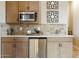 A stylish kitchenette with wooden cabinetry, stainless steel appliances, and decorative backsplash at 37795 W Padilla St, Maricopa, AZ 85138