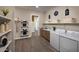 Spacious laundry room with ample shelving, modern appliances, and a convenient sink area, optimizing functionality at 37795 W Padilla St, Maricopa, AZ 85138