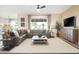 Open-concept living room featuring a large sectional sofa, ceiling fan, and neutral color scheme at 37795 W Padilla St, Maricopa, AZ 85138