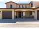 A tan two-story home with a dark brown garage door and matching door beneath an arched portico at 41448 N Eliana Dr, Queen Creek, AZ 85140