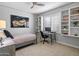 Bright bedroom featuring a motorcycle picture, a ceiling fan, and a desk by a window with plantation shutters at 4615 E Navigator Ln, Phoenix, AZ 85050